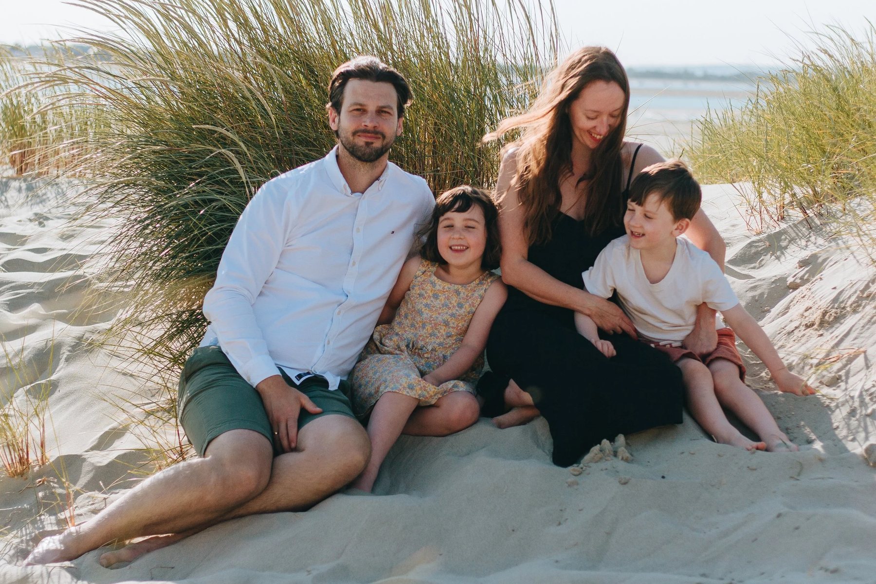 A family sitting together in the marram grass at West Wittering, out of the wind